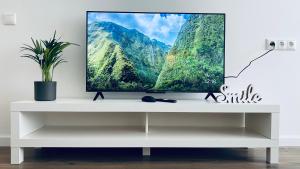 a television on a white stand with a mountain at Church Hill Apartment in Daugavpils