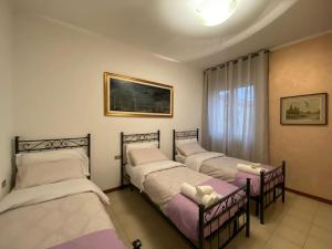 three beds in a room with a window at Fronte Fiera Apartment in Pero