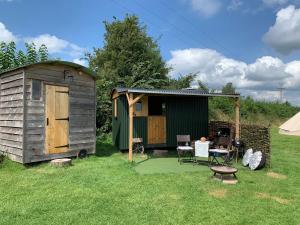 a small shed and a table and chairs in a yard at Willowdene shepherds hut in Oswestry