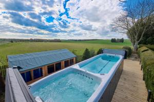 a hot tub on a deck next to a house at Luxurious 5-Bed House with Pool, Hot Tub & Parking in Eastry