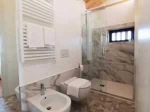 Baño blanco con aseo y lavamanos en Chalet Dolce Colle, en Volpago del Montello