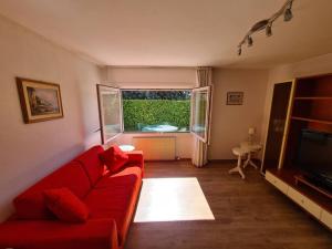 een woonkamer met een rode bank en een televisie bij Casa Sole in Costermano