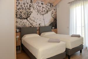 2 camas individuales en un dormitorio con papel pintado en Bed and Breakfast NAVIS en Nave San Rocco