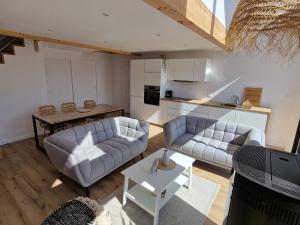 a living room with two couches and a table at LES PORTSALLAISES piscine ou spa à 300m de la plage in Ploudalmézeau