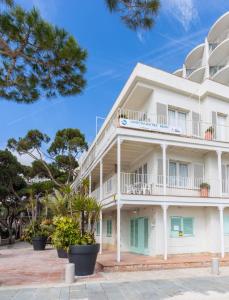 a large white building with green shutters at Apartamentos Aromar in Platja d'Aro