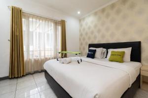 una camera da letto con un grande letto bianco e una finestra di Urbanview Hotel Gunung Geulis Village by RedDoorz a Bogor