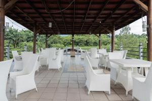 een rij witte tafels en stoelen op een patio bij Urbanview Hotel Gunung Geulis Village by RedDoorz in Bogor