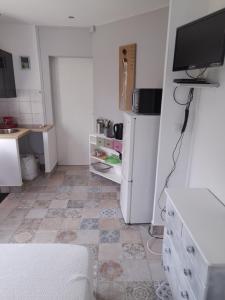 a kitchen with a white refrigerator and a tiled floor at LA DATCHA in Saujon