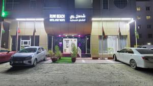 dois carros estacionados num parque de estacionamento em frente a um edifício em Ruwi Beach Hotel Apartments - MAHA HOSPITALITY GROUP em Sharjah