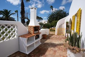 a courtyard with a brick fireplace and a white fence at Villa PACA Algarve Vilamoura 8 personnes in Quarteira
