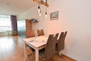 a dining room table with chairs and a refrigerator at Haus "Panorama" Appartement PAN087 in Duhnen