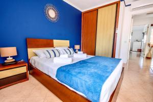 ein Schlafzimmer mit einem großen Bett mit einer blauen Wand in der Unterkunft Villa PACA Algarve Vilamoura 8 personnes in Quarteira + 21 Fotos