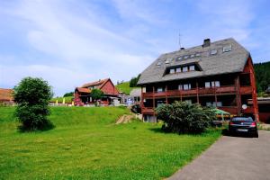 a large house on a green field with a car parked in front at B und B Titisee Hotel Sonnenmatte nahe Badeparadies in Titisee