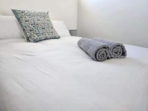 a white bed with towels and a pillow on it at Corner Cottage in Cape Town