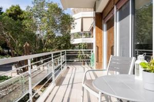 balcón con mesa blanca y sillas en Flisvos Marina refurbished apartment, en Atenas