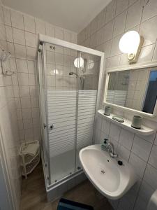 een witte badkamer met een douche en een wastafel bij Haus Gizella in Harkány