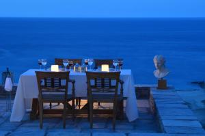 a table with wine glasses and a statue of a bust at Aegea Blue Cycladic Resort in Zorgos 