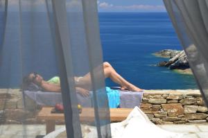 a woman laying on a bed looking out at the ocean at Aegea Blue Cycladic Resort in Zorgos 