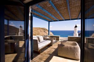 a porch with a couch and chairs and the ocean at Aegea Blue Cycladic Resort in Zorgos 