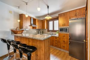 eine Küche mit Holzschränken und einem Kühlschrank aus Edelstahl in der Unterkunft Casilla de Adela in Albuñuelas
