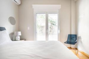 a white bedroom with a large bed and a window at Flisvos Marina refurbished apartment in Athens