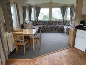 Natalies Retreat Skipsea Sands في Ulrome: غرفة معيشة مع طاولة وكراسي وأريكة