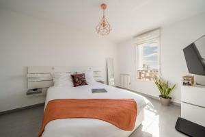 - une chambre blanche avec un lit et une télévision dans l'établissement Large and bright nest with a clear view of the sea, à Montpellier