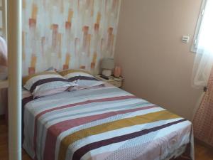 a small bedroom with a bed with a striped blanket at Chez Mamie Riclaude in Orsan