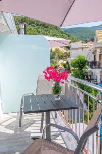 un jarrón de flores sentado en una mesa en un balcón en Serenity Luxe Suites, en Parga