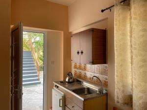 uma cozinha com um lavatório e uma porta para uma escadaria em Andreas Studios em Svoronata