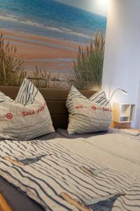 a bed with pillows and a painting of a beach at Appartement "Ostseeoase" in Heiligenhafen