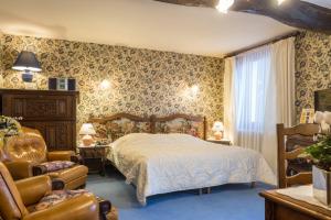 a bedroom with a bed and a chair at Hostellerie Sarrasine - M&acirc;con Est in Replonges