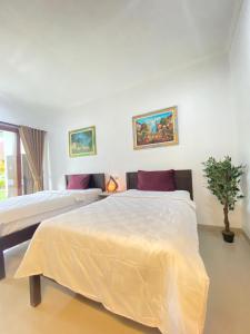 a bedroom with two beds and a potted plant at Padang-Padang Sari Homestay in Uluwatu