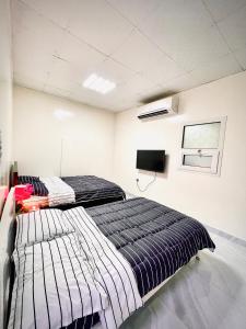 1 dormitorio con 2 camas y TV de pantalla plana en Private 2Bedroom Villa with T&B and Kitchenette near Abu Dhabi International Airport en Abu Dabi