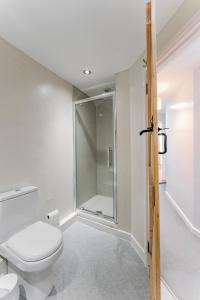 a white bathroom with a toilet and a shower at Bar Lane Cottage - Norfolk Cottage Agency in Reepham