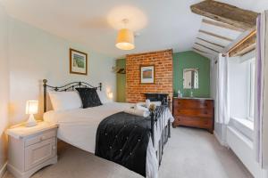 a bedroom with a bed and a brick wall at Bar Lane Cottage - Norfolk Cottage Agency in Reepham