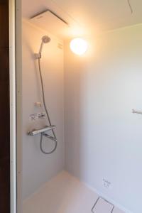 y baño con ducha y pared blanca. en PICNIC　GARDEN, en Awaji