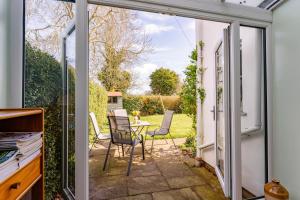 an open door to a patio with chairs and a table at Bar Lane Cottage - Norfolk Cottage Agency in Reepham
