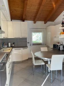 a kitchen with white cabinets and a table and chairs at Casa delle Olive 1 in Oliveto Lario