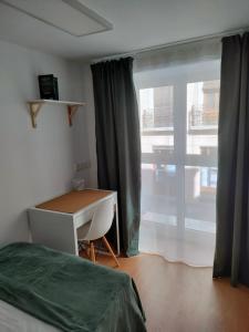 a bedroom with a bed and a desk and a window at La Paz in Almansa