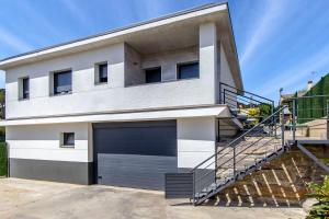 a white house with a garage door and stairs at Catalunya Casas Modern Vacation Paradise 'Villa Ainmi' on the Costa Brava! in Sils