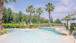 a swimming pool with palm trees and a bridge at Relais du Lac Village - Italian Homing in Desenzano del Garda