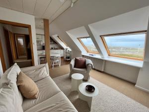 ein Wohnzimmer mit einem Sofa, einem Stuhl und 2 Fenstern in der Unterkunft Haus Janus 3 - Wohnung 4 in Norderney