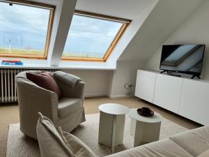 a living room with a couch and a tv and two windows at Haus Janus 3 - Wohnung 4 in Norderney