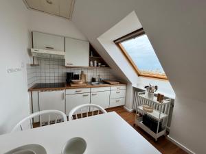 eine Küche mit einem Tisch und Stühlen sowie einem Fenster in der Unterkunft Haus Janus 3 - Wohnung 4 in Norderney