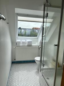 a bathroom with a shower and a toilet with a window at Haus Janus 3 - Wohnung 4 in Norderney