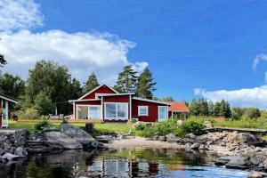 Lilla Skårudden في فارنامو: بيت احمر بجانب نهر فيه صخور