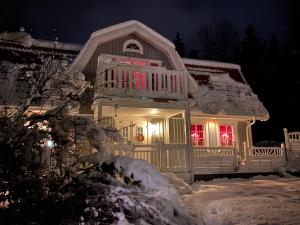 una casa cubierta de nieve por la noche con luces rojas en Family Holiday and Business Home with a Garden in Kallfors, Stockholm near a Golf Course, Lakes, the Baltic Sea, Forests & Nature en Järna