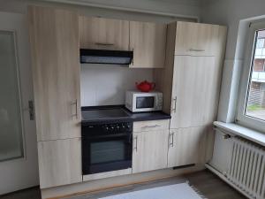cocina con armarios de madera y microondas en Westküste Ferienwohnung, en Heide