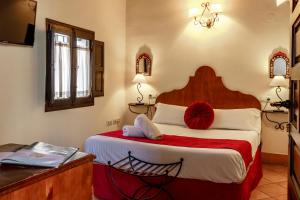 een slaapkamer met een groot bed en een rode deken bij Casa del Capitel Nazarí in Granada